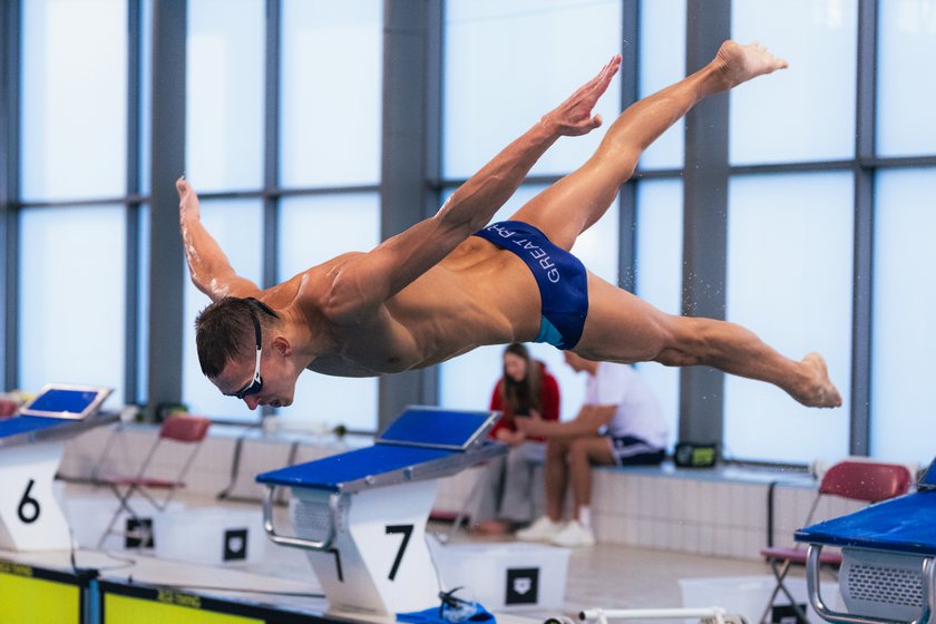 Pływak wykonuje skok startowy, widok z boku basenu. PGE Grand Prix Puchar Polski, Oświęcim, 15.03.2026.